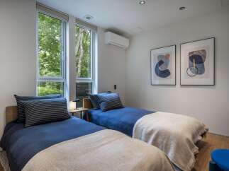 This bright bedroom features two twin beds with blue bedding and striped pillows, perfect for guests or children.
