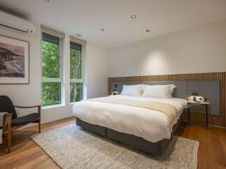 Experience serene living in this beautifully appointed bedroom, featuring a plush king-sized bed adorned with crisp white linens and a cozy throw.