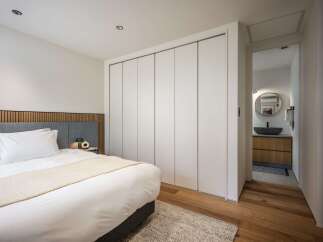 Experience modern comfort in this beautifully appointed bedroom, featuring a plush bed with crisp white linens and a cozy throw.