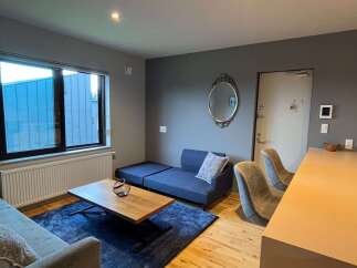 Experience modern living in this stylish apartment featuring a comfortable blue sofa and a sleek wooden coffee table.