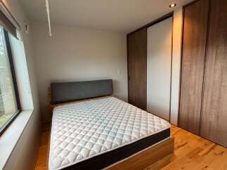 Discover modern comfort in this serene bedroom, featuring a plush mattress on a sleek wooden bed frame.