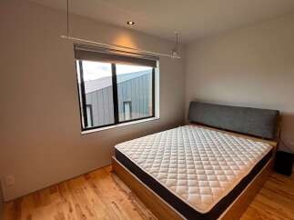 Experience modern comfort in this stylish bedroom, featuring a plush mattress on a sleek wooden bed frame.