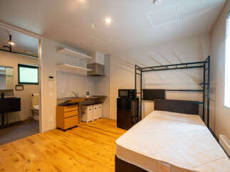 Discover this modern studio apartment featuring a compact kitchenette with ample storage and a sleek sink area.