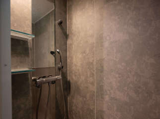 Experience modern comfort in this bathroom featuring a sleek shower with a handheld wand and a built-in thermostatic mixer for precise temperature control.