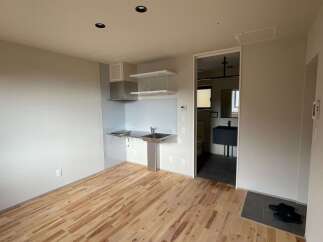 Discover modern living in this studio apartment featuring a sleek kitchenette with a stainless steel sink and countertop, perfect for preparing meals.