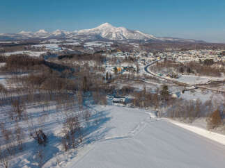 Experience the serene beauty of this winter wonderland, featuring a charming town nestled at the foot of majestic snow-capped mountains.