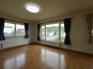 Experience comfortable living in this spacious room featuring a large window with scenic views and elegant blue curtains.
