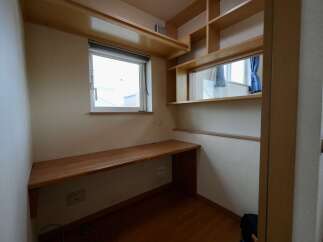 This compact workspace features a built-in wooden desk and shelving, perfect for a home office or study nook.