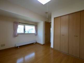 This spacious room features a large window with light pink curtains, offering a view of the outdoors.