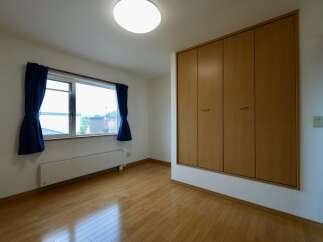 This spacious room features a large window with blue curtains, offering natural light and a view of the outdoors.