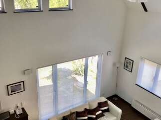 Experience modern living in this spacious, light-filled living room featuring a soaring vaulted ceiling and a sleek sectional sofa.