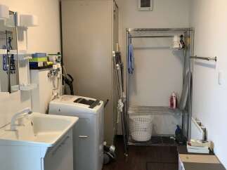 This laundry room offers a practical and organized space with a top-loading washing machine and a separate sink area.