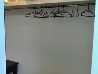 Discover ample storage space in this well-organized closet, featuring a sturdy hanging rod and multiple hangers.