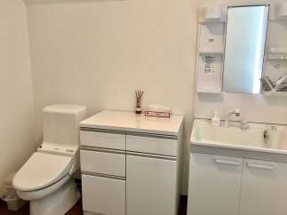 This modern bathroom features a sleek white toilet with a bidet function, complemented by a matching vanity with ample storage.