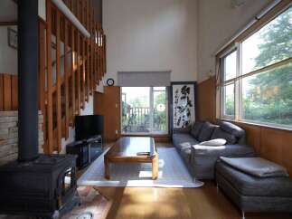 Experience cozy living in this charming home featuring a rustic wood-burning stove and a beautiful wooden staircase.