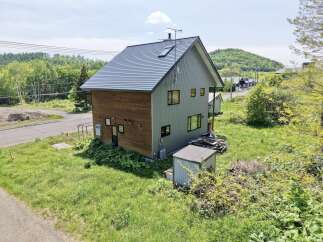 Discover this charming two-story home featuring a unique blend of wood and corrugated metal siding, offering a modern rustic aesthetic.