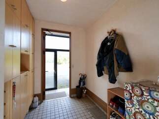 Step into this welcoming entryway featuring ample storage with floor-to-ceiling wooden cabinets and a convenient coat rack.