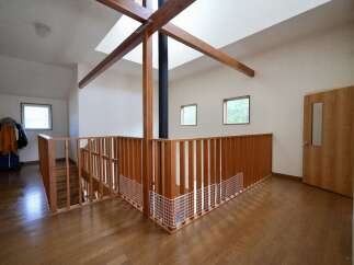 This spacious interior features a striking wooden beam structure overhead, complemented by a central black chimney.
