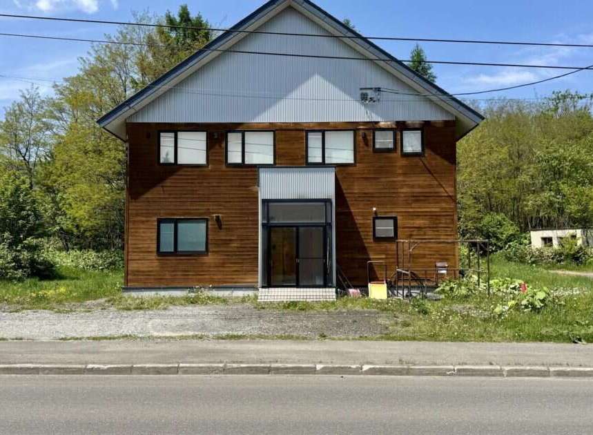 Charming wooden house with a modern entrance, featuring multiple windows for natural light.