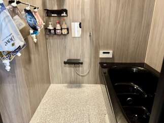Experience a spa-like retreat in this modern bathroom, featuring a sleek black bathtub and a convenient shower area with ample storage.