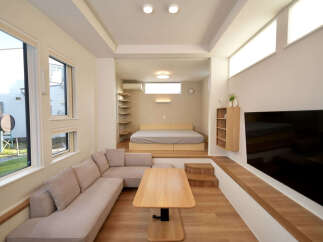 Discover modern living in this stylish studio apartment, featuring a spacious sectional sofa and a sleek wooden coffee table perfect for relaxation.