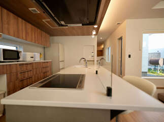 Experience modern living in this stunning kitchen featuring sleek wooden cabinetry and a spacious island with a built-in stovetop.