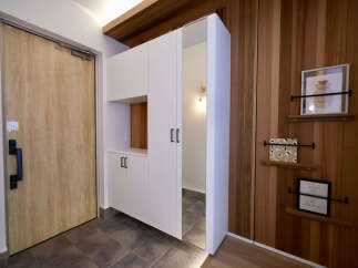 Step into a welcoming entryway featuring a light wood door with a modern black handle, complemented by sleek white cabinetry and a warm wood accent wall.