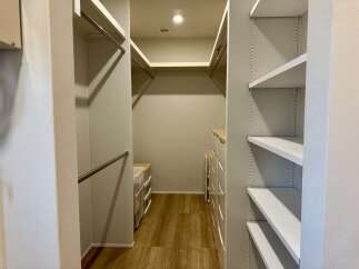 Discover ample storage in this spacious walk-in closet, featuring multiple hanging rods and extensive shelving.