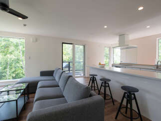 Experience modern living in this open-concept space featuring a sleek grey sectional sofa and a stylish kitchen island with bar stools.