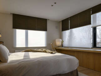 Experience modern comfort in this serene bedroom, featuring a plush bed adorned with a luxurious throw.