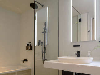 Experience modern luxury in this stunning bathroom featuring a sleek bathtub and a separate glass-enclosed shower with a rainfall showerhead.