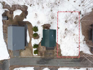 Discover this aerial view of a property featuring a charming green-roofed house nestled amongst trees and snow.