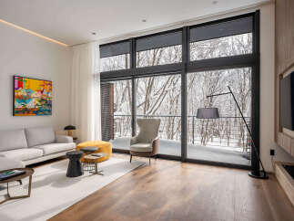 Experience modern luxury with this stunning living room, featuring a sectional sofa, a vibrant abstract artwork, and a cozy armchair.