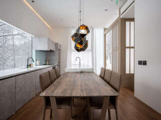 Experience modern living with this stunning dining area featuring a large wooden table and comfortable chairs, perfect for family gatherings.