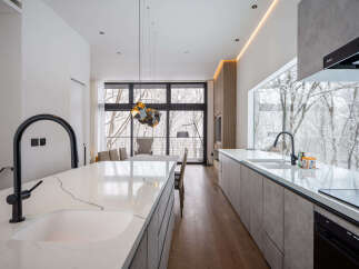 Experience modern luxury in this stunning kitchen featuring a sleek waterfall island with a contemporary black faucet.