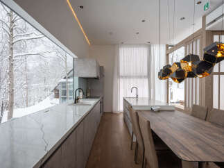 Experience modern luxury in this stunning kitchen and dining area, featuring a sleek marble countertop island and a large window overlooking a serene snowy landscape.