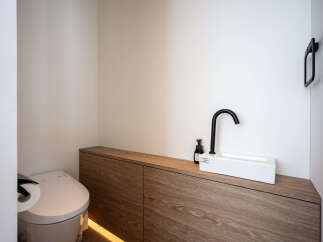 Discover modern elegance in this bathroom, featuring a sleek white sink with a matte black faucet, complemented by a minimalist wooden vanity.