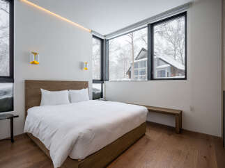Experience modern comfort in this serene bedroom, featuring a plush king-sized bed dressed in crisp white linens.