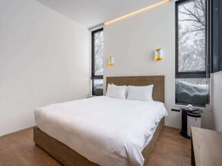 Experience ultimate comfort in this modern bedroom, featuring a plush king-sized bed with crisp white linens and a stylish wooden headboard.