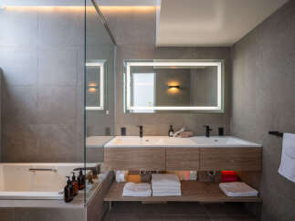 Experience modern luxury in this stunning bathroom featuring a spacious soaking tub and a sleek double vanity with integrated lighting.