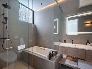 Experience modern luxury in this stunning bathroom featuring a sleek glass-enclosed shower and a deep soaking tub, perfect for unwinding.