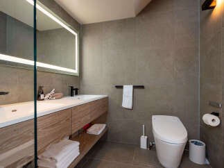 Experience modern luxury in this stunning bathroom, featuring a sleek vanity with ample storage and a large, illuminated mirror.