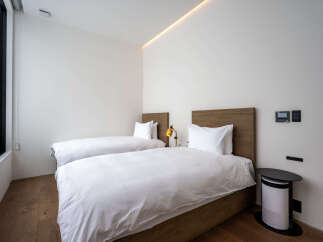 Experience modern comfort in this stylish bedroom featuring two twin beds with crisp white linens and warm wooden headboards.