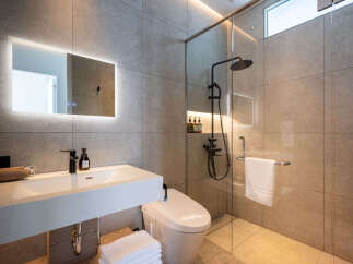 Experience modern luxury in this stunning bathroom, featuring a sleek vanity with a contemporary faucet and a built-in hairdryer.