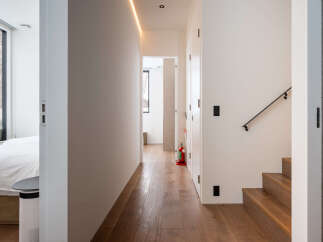 Experience modern living in this stylish hallway featuring a sleek LED strip light and warm hardwood floors.