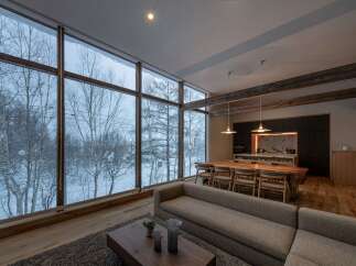 Experience breathtaking winter views from this stunning living space, featuring expansive floor-to-ceiling windows that showcase a serene snow-covered landscape.