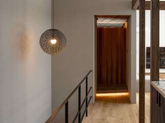 Experience modern living with this stunning interior featuring a sleek black metal railing guiding you down a beautifully lit hallway.