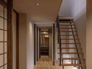 Discover modern living with this stunning staircase featuring warm wooden treads and sleek black metal railings, seamlessly integrated into a hallway with natural wood flooring.