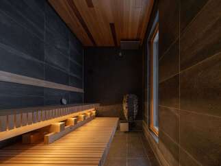 Experience ultimate relaxation in this modern sauna featuring dark tiled walls and a warm wooden ceiling.