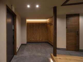 Step into a modern entryway featuring a sleek dark door and a warm wooden accent wall with integrated coat hooks.
